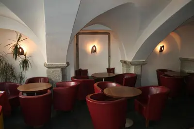 a restaurant with red chairs and tables and a mirror at Hotel Krone in Brunico