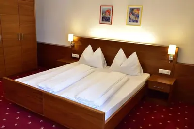 a bedroom with a bed with white sheets and pillows at Hotel Krone in Brunico