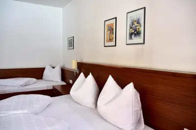 a hotel room with two beds with white pillows at Hotel Krone in Brunico