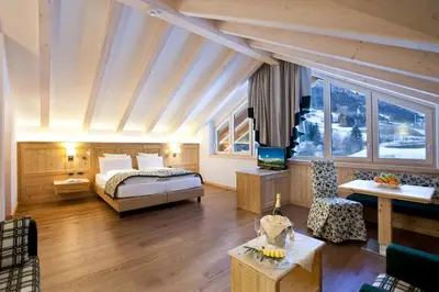 a bedroom with a bed and a living room at Rio Stava Family Resort & Spa in Tesero