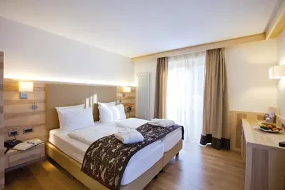 a hotel room with a large bed and a window at Rio Stava Family Resort & Spa in Tesero