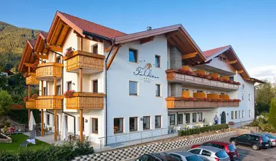 a building with balconies and cars parked in a parking lot at Hotel Falken in Falzes