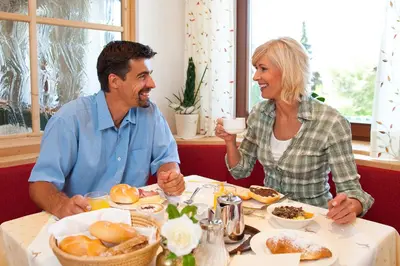 a man and woman sitting at a table eating food at Hotel Falken in Falzes
