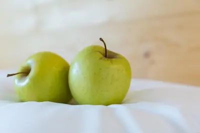 two green apples sitting on top of a table at Hotel Falken in Falzes