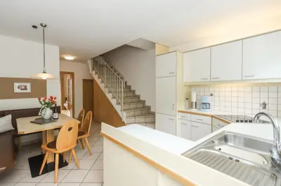 a kitchen with white cabinets and a staircase at Residence Hof am Keller in Montagna