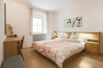 a bedroom with a bed and a desk and a window at Residence Hof am Keller in Montagna