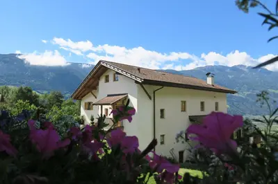 a white house with purple flowers in front of it at Winklerhof in Parcines