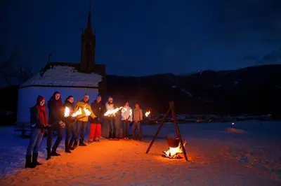 a group of people standing around a fire at night at Agalma in Brunico