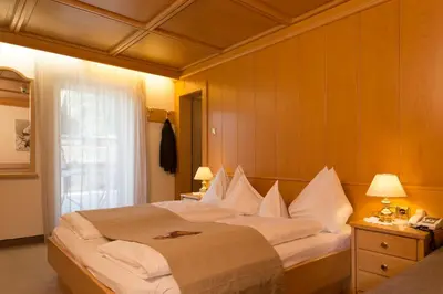 a bedroom with a large bed with white pillows at Hotel Burgfrieden in Gais