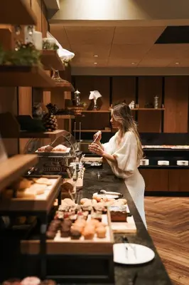 a woman standing behind a counter in a bakery at Sporthotel Obereggen in Obereggen