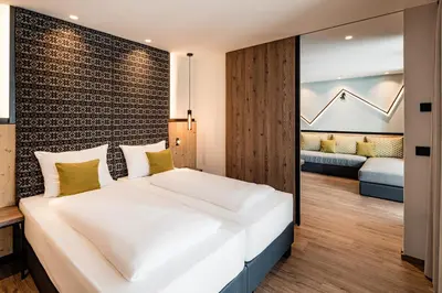 a bedroom with a large white bed with a brick wall at Sporthotel Obereggen in Obereggen