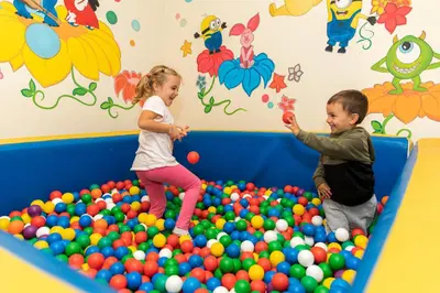 a boy and a girl playing in a large ball pit at Hotel Garden in Moena