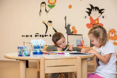 two children sitting at a table playing with art at Hotel Garden in Moena