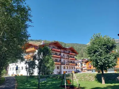 a large apartment building with a playground in a park at Park Hotel Avisio in Soraga