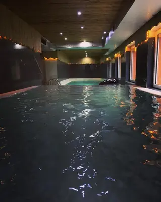 an indoor swimming pool with blue water in a building at Park Hotel Avisio in Soraga