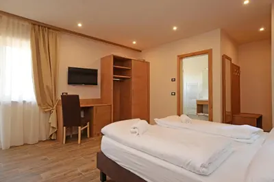 a hotel room with two beds and a desk and a television at Park Hotel Avisio in Soraga