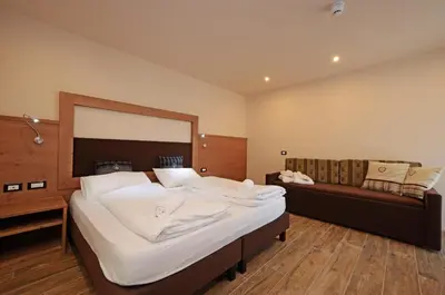 a bedroom with a large bed and a couch at Park Hotel Avisio in Soraga