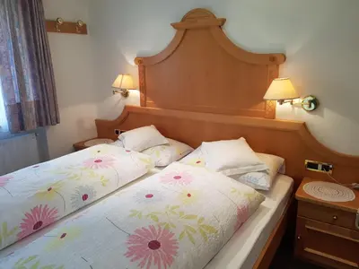 two beds in a hotel room with flowers at Garni Rubens B&B in Selva di Val Gardena
