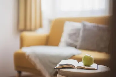 a book and an apple on a table next to a bed at Residence Chiavi D'Oro - Goldener Schlüssel in Bressanone