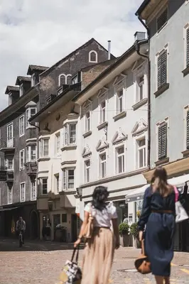 two women walking down a street in front of buildings at Residence Chiavi D'Oro - Goldener Schlüssel in Bressanone