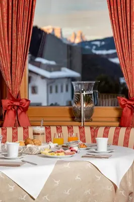 a table with a plate of food and a window at Garni Hotel Rosengarten B&B in Selva di Val Gardena