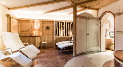 a salon with white chairs in a room at Garni Hotel Rosengarten B&B in Selva di Val Gardena