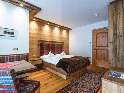a bedroom with a bed and a wooden wall at Garni Hotel Rosengarten B&B in Selva di Val Gardena