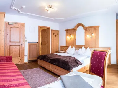 a bedroom with a large bed in a room at Garni Hotel Rosengarten B&B in Selva di Val Gardena