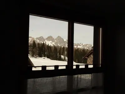 a window with a view of a snow covered mountain at Baita Casera Caviazza in Falcade