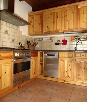 a kitchen with wooden cabinets and a stainless steel appliance at Baita Casera Caviazza in Falcade