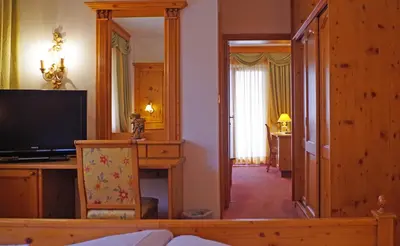 a living room with a mirror and a television at Hotel Bergland in Schenna