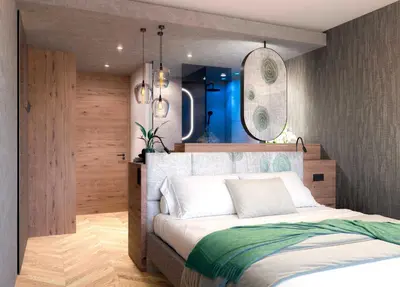 a bedroom with a bed with a mirror on the wall at Hotel Bergland in Schenna
