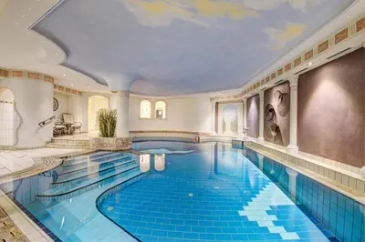 an indoor swimming pool with a large blue swimming pool at Hotel Bergland in Schenna