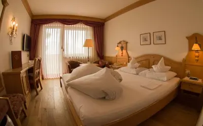 a bedroom with a large bed with white pillows at Hotel Bergland in Schenna