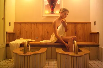 a woman sitting in a tub in a bath room at Hotel Bergland in Schenna