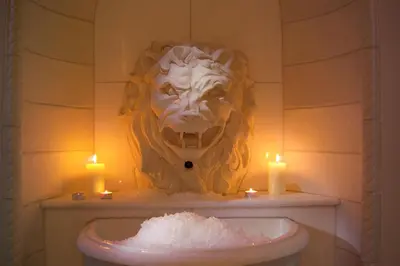a mask on the wall of a bathroom with candles at Hotel Bergland in Schenna