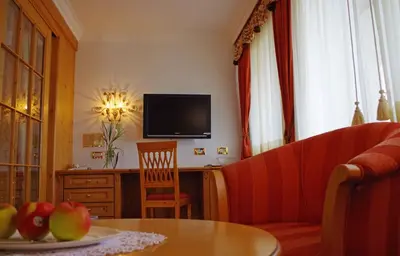 a living room with a couch and a table and a television at Hotel Bergland in Schenna