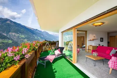 a hotel with chairs and umbrellas in the grass at Der Verdinser Hof in Schenna