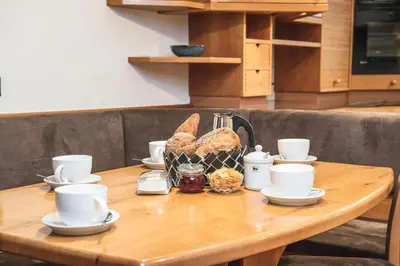 a table with cups and a basket of bread on it at Arjentel Lodge in Selva di Val Gardena