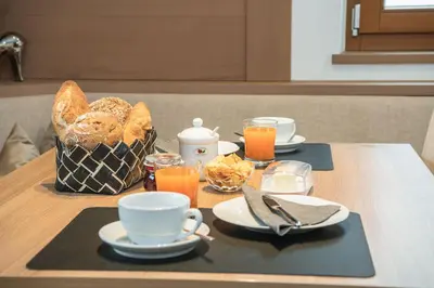 a table with plates and cups of coffee and a basket of bread at Arjentel Lodge in Selva di Val Gardena