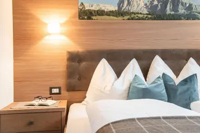 a bedroom with a bed with white and blue pillows at Arjentel Lodge in Selva di Val Gardena