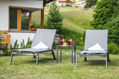 two chairs and a table in the grass at Arjentel Lodge in Selva di Val Gardena