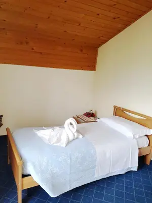 a bedroom with a white bed with a wooden ceiling at Albergo Posta in Colle Santa Lucia