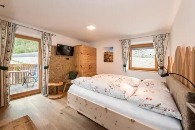 a bedroom with a bed and a balcony at Planatschhof in Villnoss