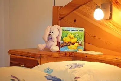 a stuffed elephant sitting on a head board with a book at Planatschhof in Villnoss