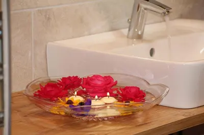 a glass bowl with candles and red flowers on a sink at Planatschhof in Villnoss