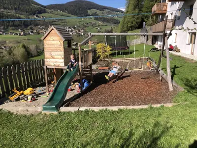 a playground with two children playing on a slide at Planatschhof in Villnoss