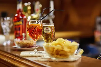 two glasses of champagne and a bowl of chips on a table at GH Hotel Monzoni in Pozza di Fassa