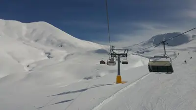 a ski lift with skiers on a snowy mountain at GH Hotel Monzoni in Pozza di Fassa