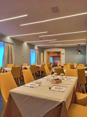 a conference room with tables and yellow chairs at GH Hotel Monzoni in Pozza di Fassa